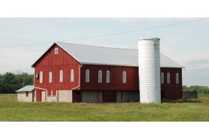 Red farm building located in field.